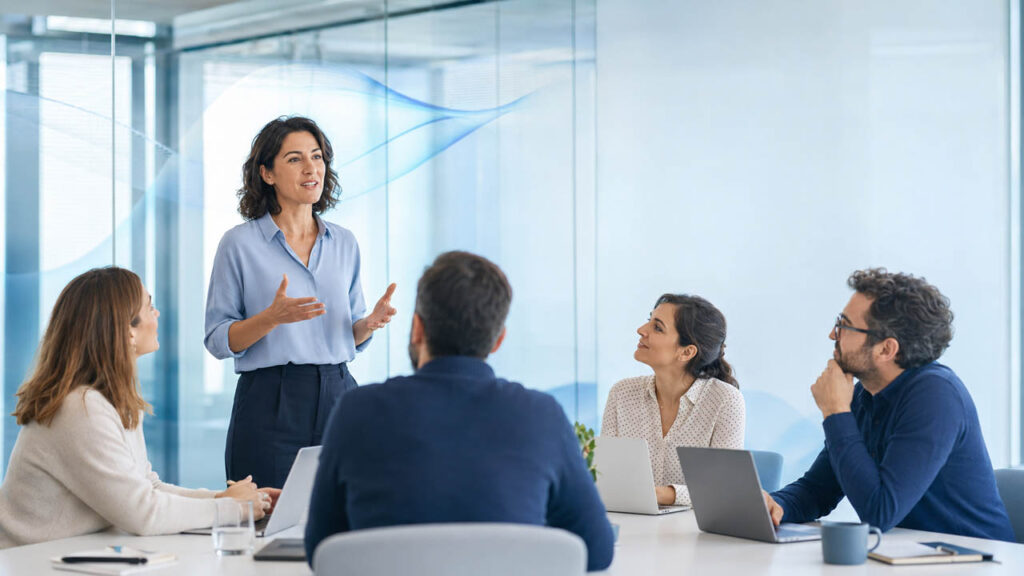 Formadora impartiendo formación obligatoria en IA a un equipo empresarial en una sala corporativa